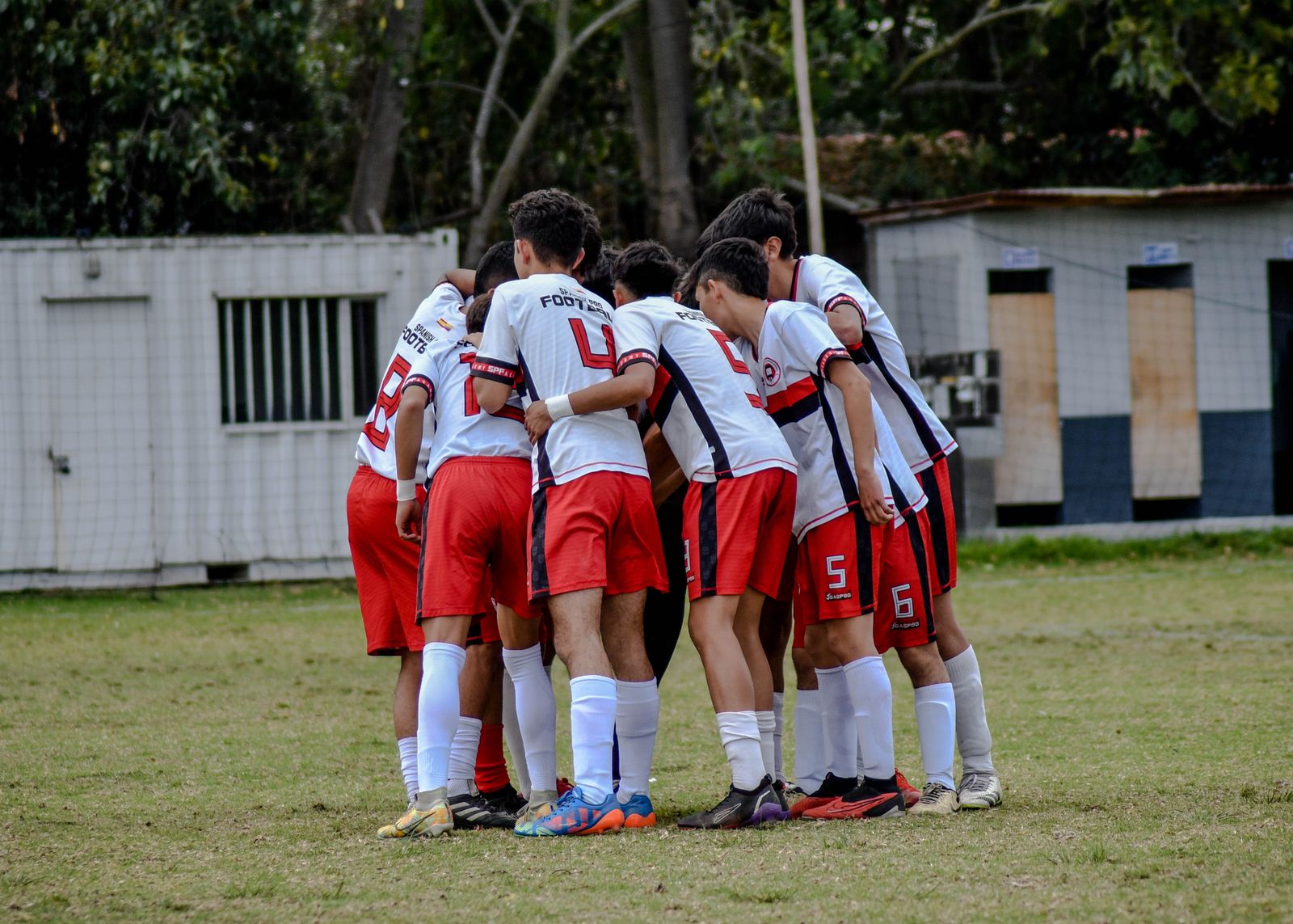 Young soccer teammates with arms around each other in a huddle